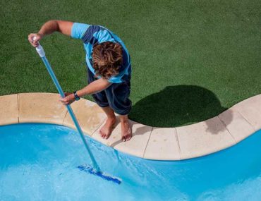 man cleaning inground pool