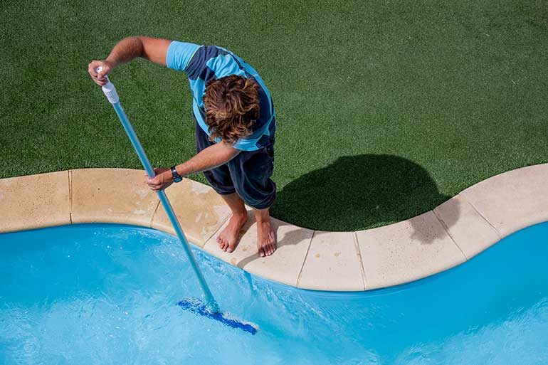 man cleaning inground pool